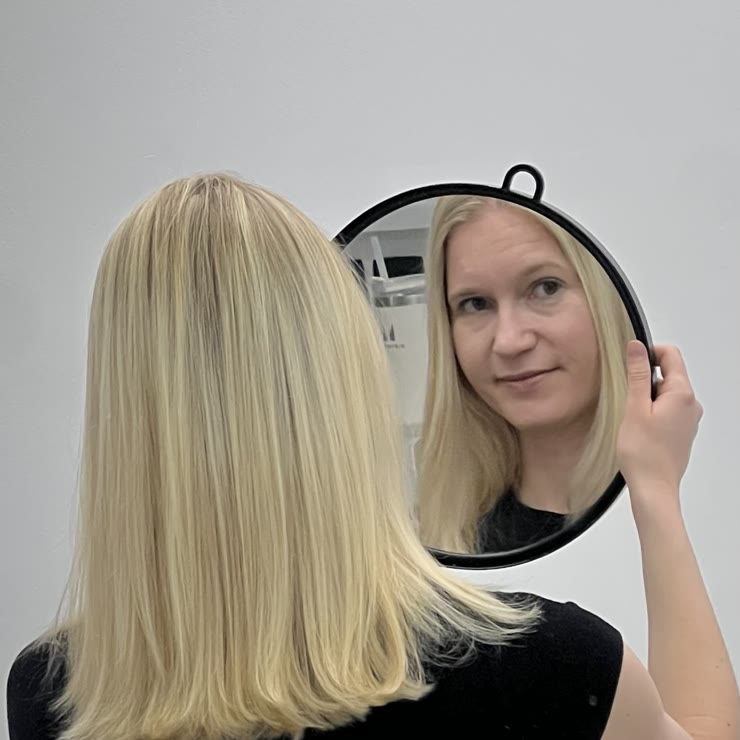 Stranka z ročnim zrcalom in platinasto blond bob pričesko
